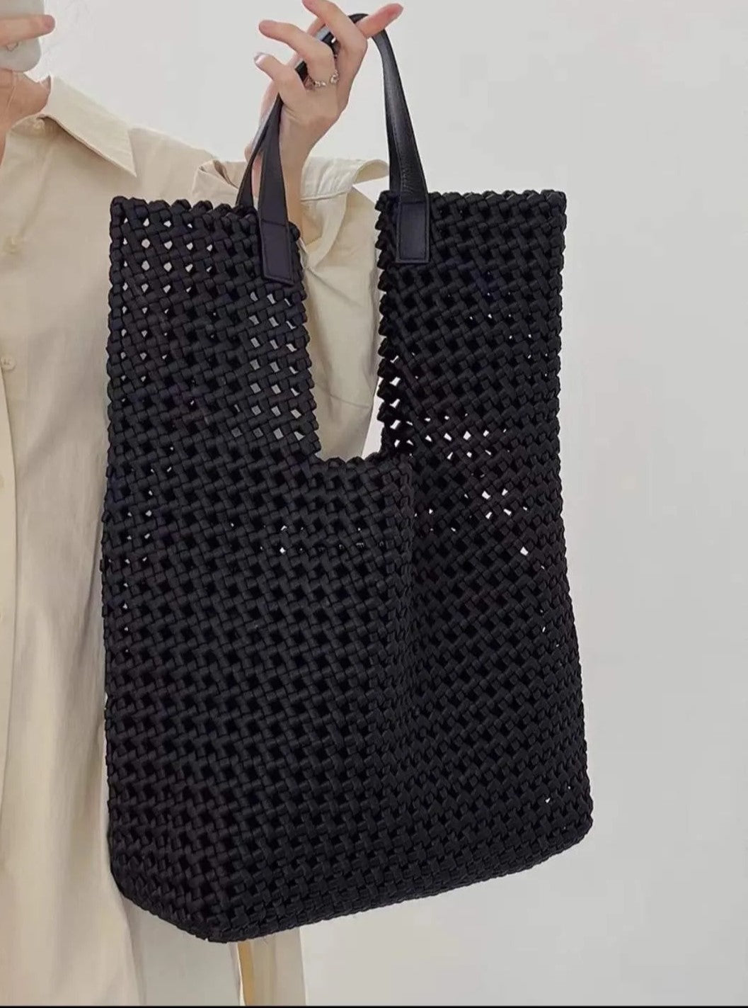 Bolso shopper de piel negro con tejido entrelazado. Diseño amplio y elegante, ideal para el día a día. Asas resistentes y cierre seguro.