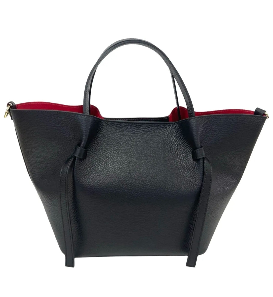 Bolso tote de piel negra con interior rojo, asas resistentes y detalles de lazo lateral, ideal para un look elegante y moderno.